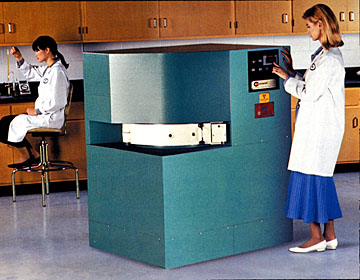 photo of two women in a lab environment with one operating a gamma irradiator