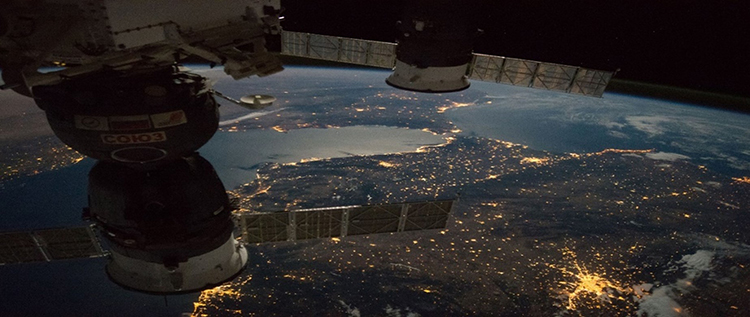 Expedition 49 crew members capture a nighttime view of the Strait of Gibraltar with a Russian Soyuz spacecraft (left) and Progress spacecraft (right) in the foreground.