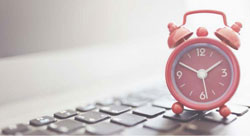 image of 10 CFR 26 Work Hour Requirements with a clock on top of a keyboard on a desk on a white grey background