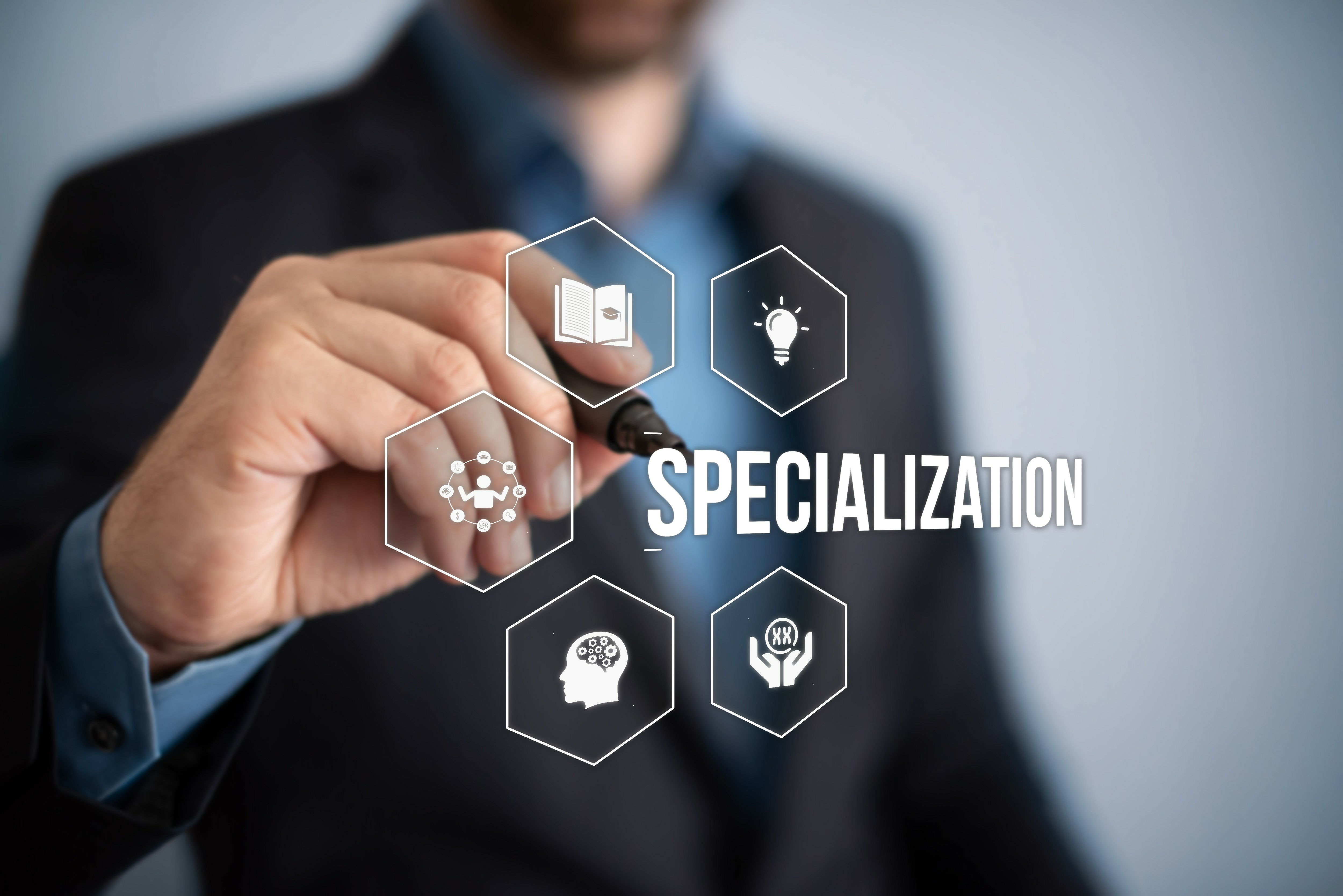 Image of a blurred person with their hand in focus holding a pen with the word 'Specialization' in white font