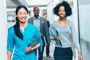  Employees walking down a hallway; two women walking side by side and smiling.