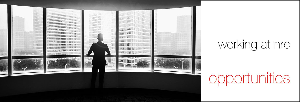 Black and white photo of a man in a suit, standing at the windows of a high-rise building several stories up and looking out, with the words 'working at nrc' and (in red font) 'opportunities' to the right of the photo on a white background.