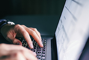 Image of hands typing on a laptop