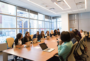 Conference room with people sitting around a rectangular table