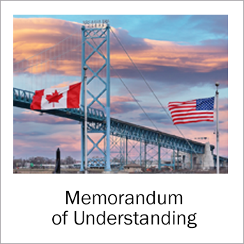 image of US and Canadian flag in front of bridge
