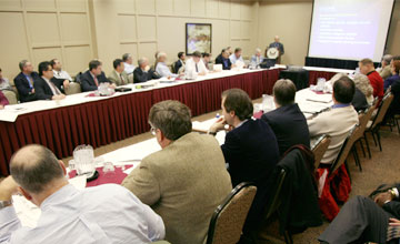 Representative photo of attendees seated around tables at a public meeting