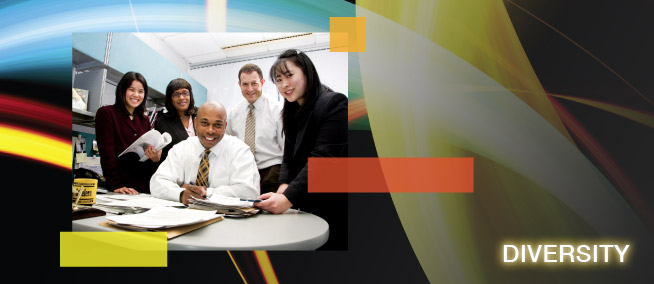 A multi-racial team of office workers gathered around a small desk and the word Diversity