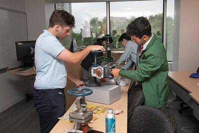 Picture of a classroom setting, equipment models on tables and students engage in hands-on activities to discover each mechanism.