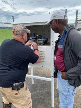 An NRC inspector observes a licensee technician during an environmental monitoring inspection.