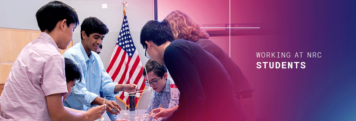 students working together to build a tower with sticks and marshmallows, in the background is a american flag on a pole, and to the right on a purple and faded into blue colored background, the words 'working at nrc' and (in bold font) 'students'