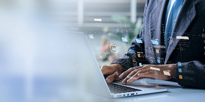 image of a laptop with icons overlaying within a person typing on keyboard