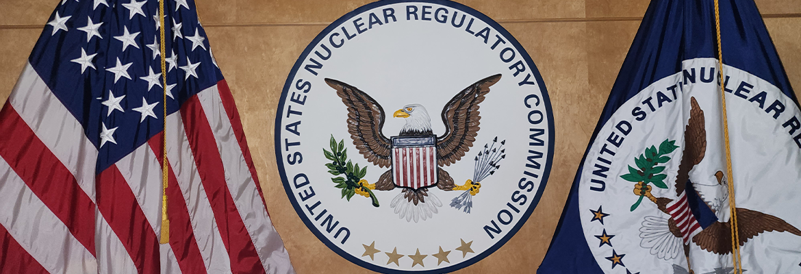image of the NRC Seal with the American Flag on the right and the NRC Flag on the left.