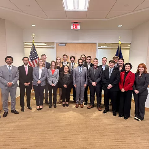 Image of a large group of people in a room smiling for the camera. 